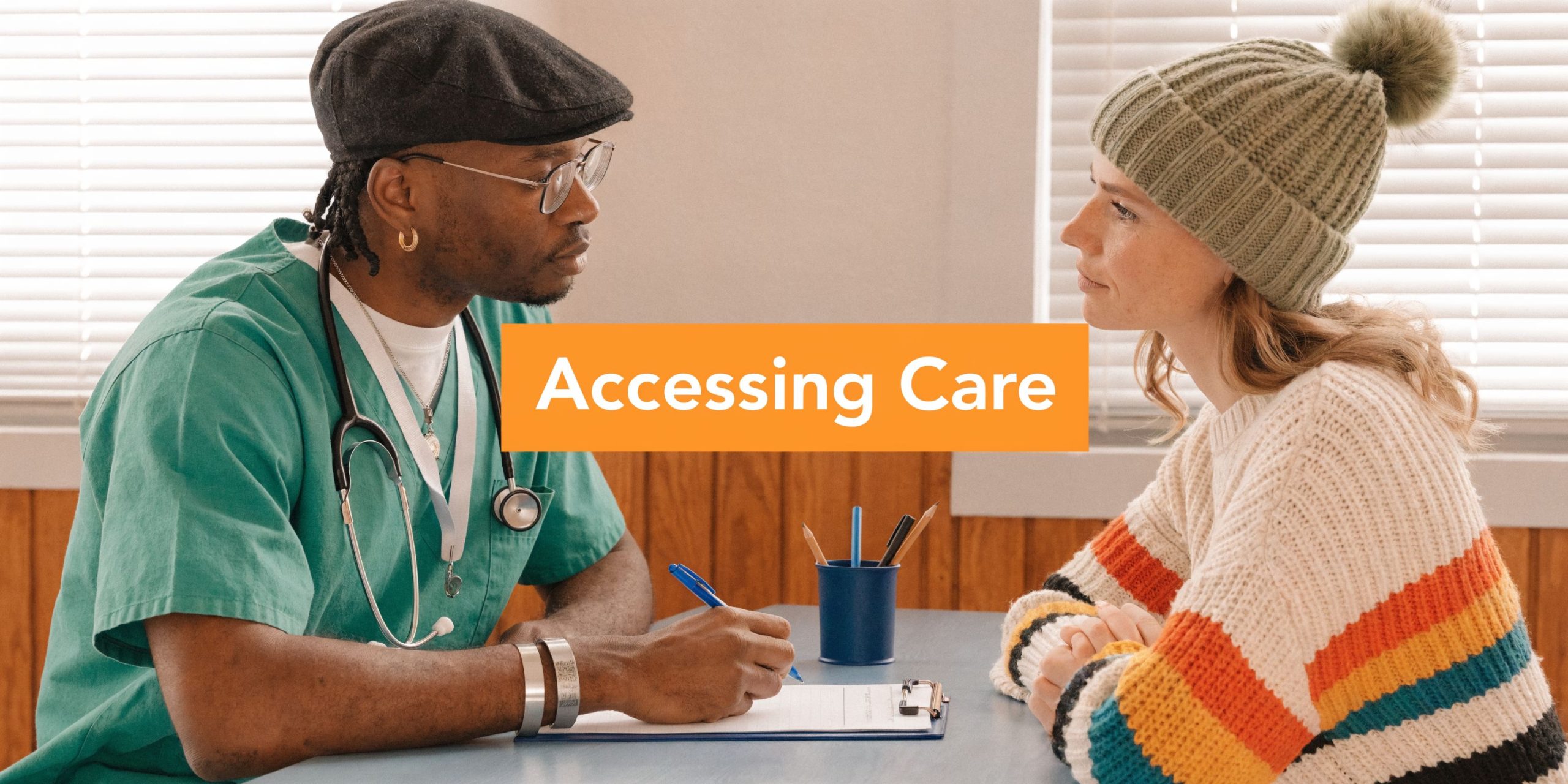 A healthcare professional sits at a desk talking to a patient during a medical consultation.