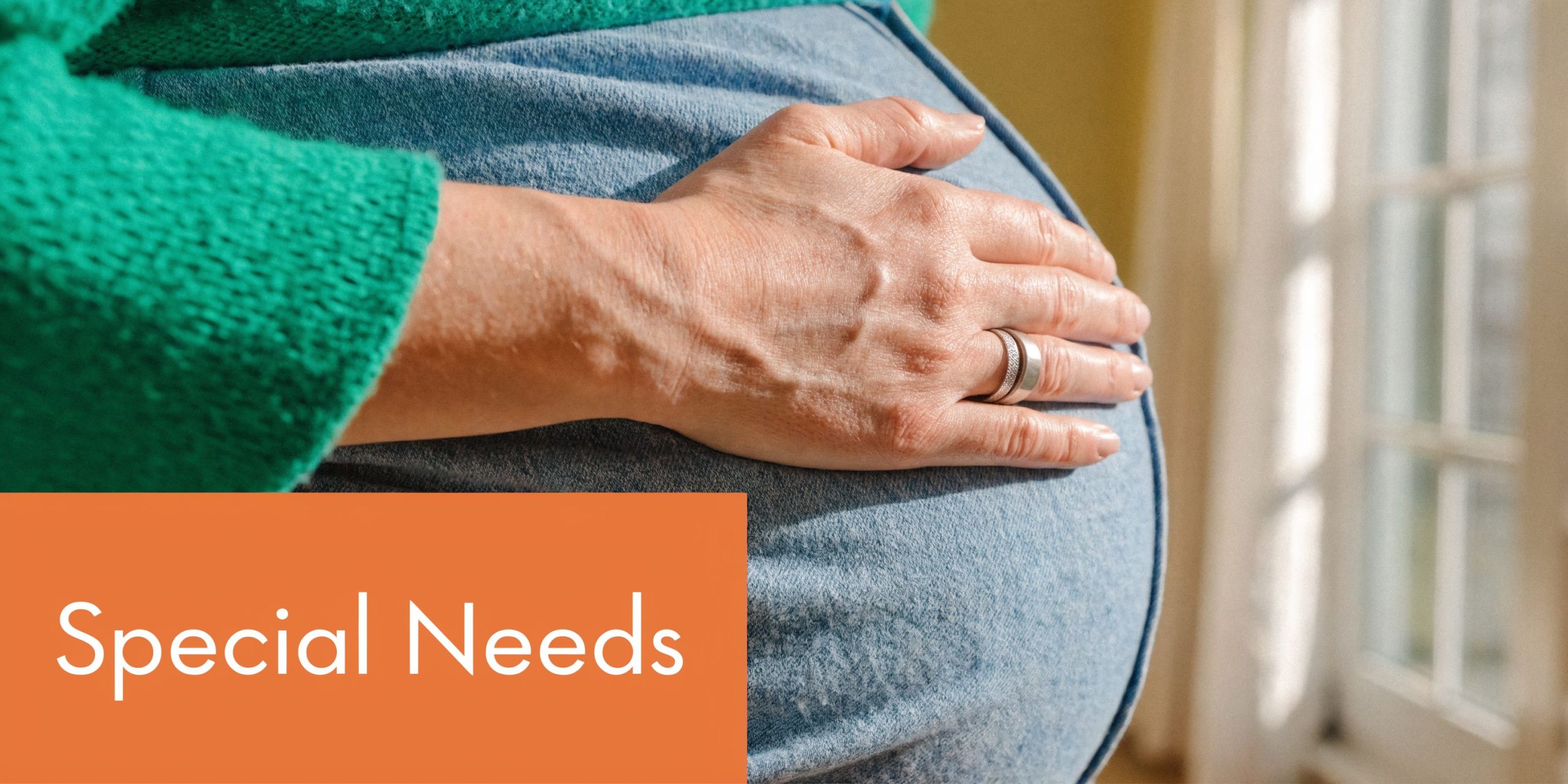 A close-up view of a pregnant woman's belly with a hand resting gently on her stomach.