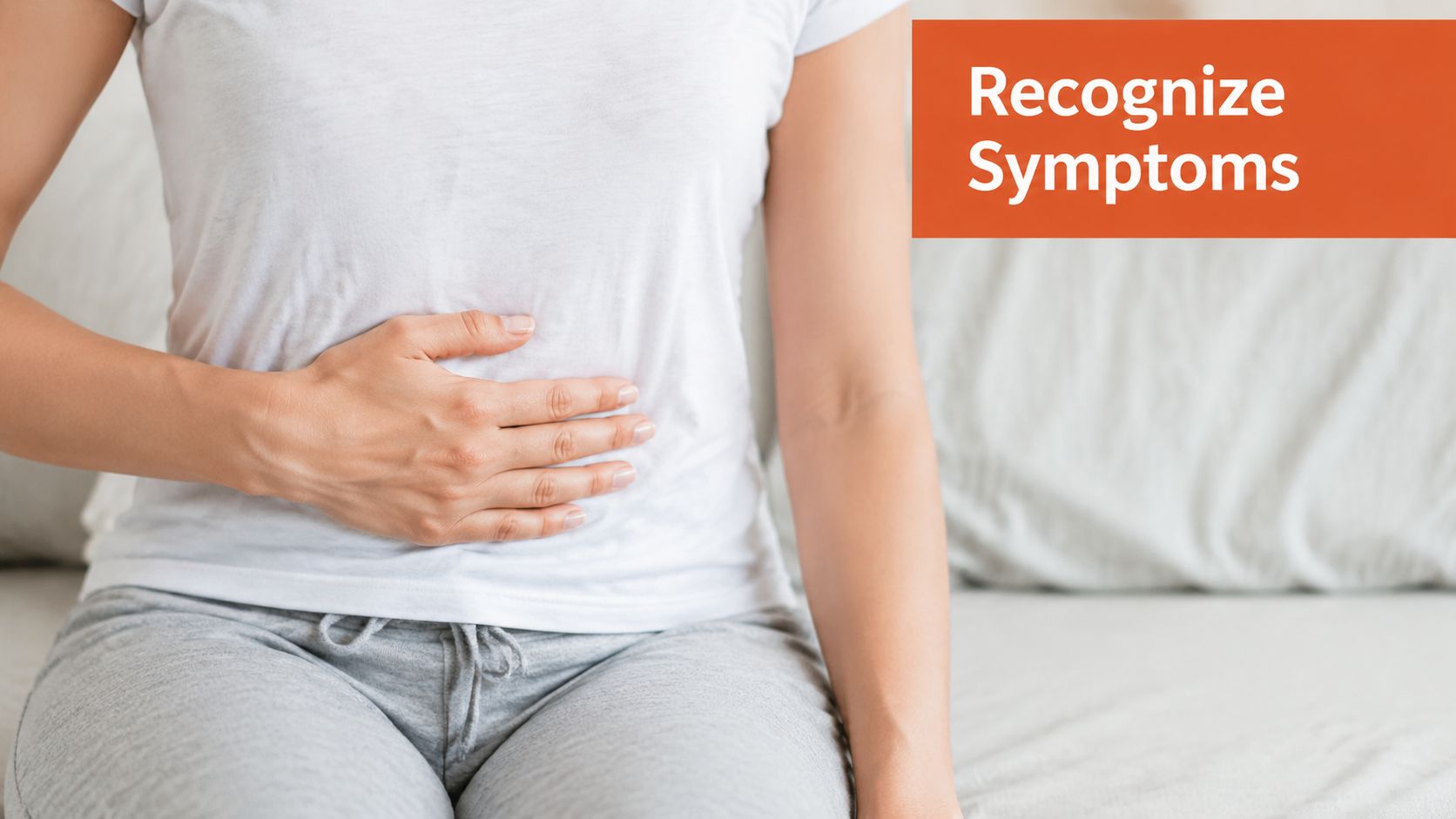 A woman holding her lower abdomen while sitting on a bed, illustrating the concept of recognizing symptoms.